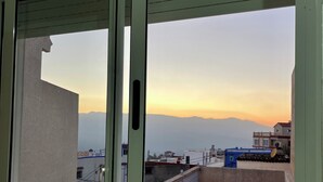 Blick vom Balkon mit Bergelandschaft und blauem Himmel.