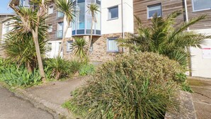 A multi-story building with a mix of stone and wood facade, featuring balconies and large windows. - Apartment 2 (Newquay)
