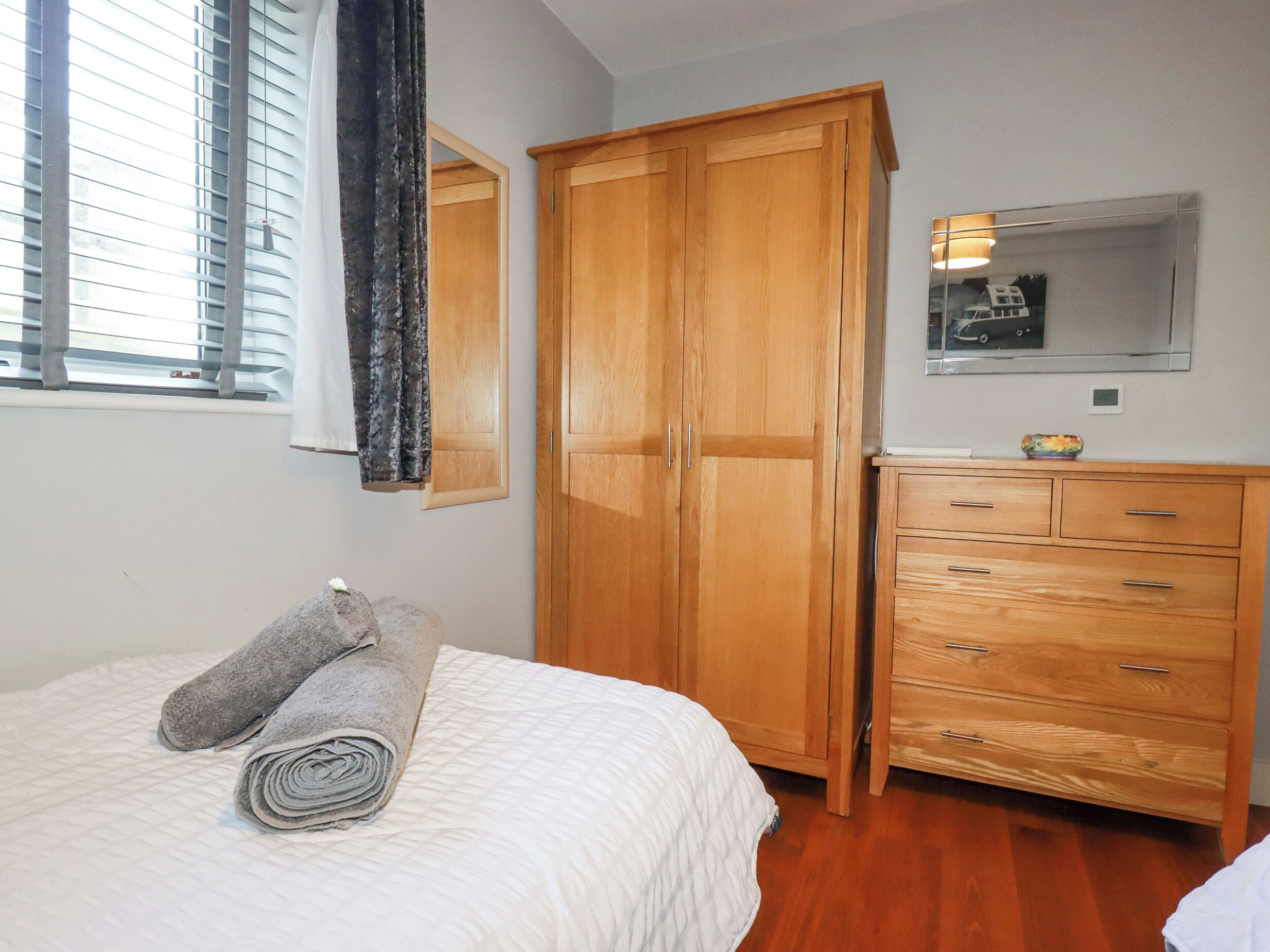 Une chambre à coucher avec un lit, une armoire en bois, une commode et un miroir.