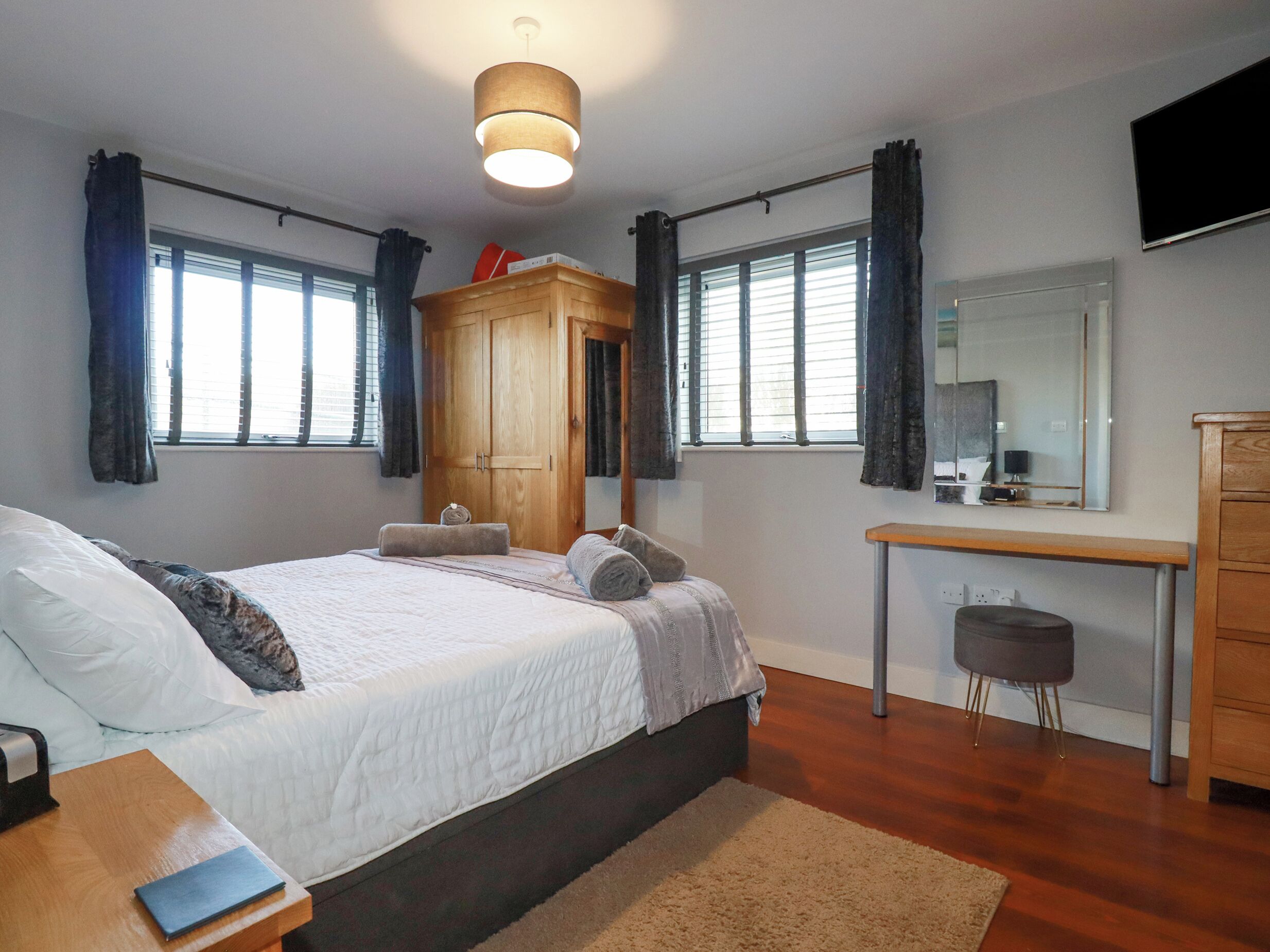 Une chambre à coucher avec un grand lit, une armoire en bois, un bureau avec une chaise et un miroir.