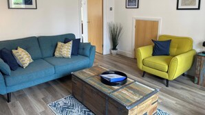 Ein Wohnzimmer mit einem blauen Sofa, einem gelben Sessel und einem Couchtisch aus Holz.