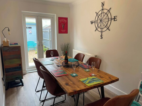 A dining area with a wooden table, chairs, and a compass wall decoration.