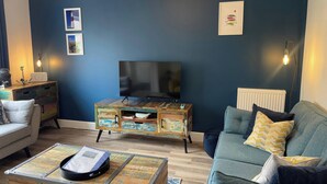 Ein Wohnzimmer mit Fernseher, Holzschrank, Sofa und Couchtisch.