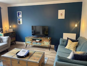 A living room with a television, a wooden cabinet, a sofa, and a coffee table.