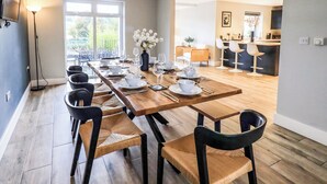 A modern dining area with a long wooden table set for six, surrounded by black chairs with woven seats. - Pen-y-ghent (Carnforth)