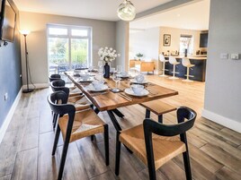 Un comedor moderno con una larga mesa de madera dispuesta para seis personas, rodeada de sillas negras con asientos de mimbre.