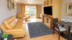 A living room with a sofa, TV, fireplace, and dining area. - 315 Filey Road (Scarborough)