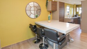 A modern kitchen with a central island, bar stools, and a decorative mirror. - 315 Filey Road (Scarborough)
