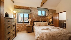Ein Schlafzimmer mit Backsteinwand, Holzbettgestell und einer Kommode mit Schubladen.