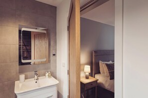 Un baño moderno con lavamanos, espejo y artículos de aseo.