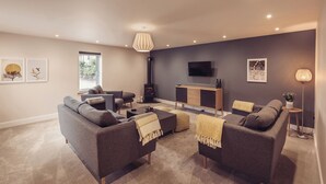 A modern living room with a sofa set, a coffee table, a fireplace, and a TV mounted on the wall. - Ingleborough (Carnforth)