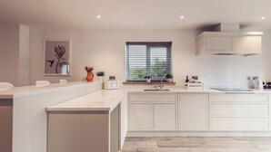 A modern kitchen with white cabinetry, a central island, a window with blinds, and a framed artwork on the wall. - Ingleborough (Carnforth)