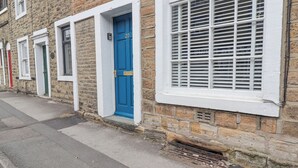 A row of terraced houses with distinct front doors, some with mail slots, and a window with white shutters. - Birch Cottage (Skipton)