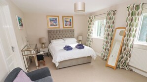 A bedroom with a bed, bedside tables, a chair, a mirror, and curtains. - Archway House (Haverfordwest)