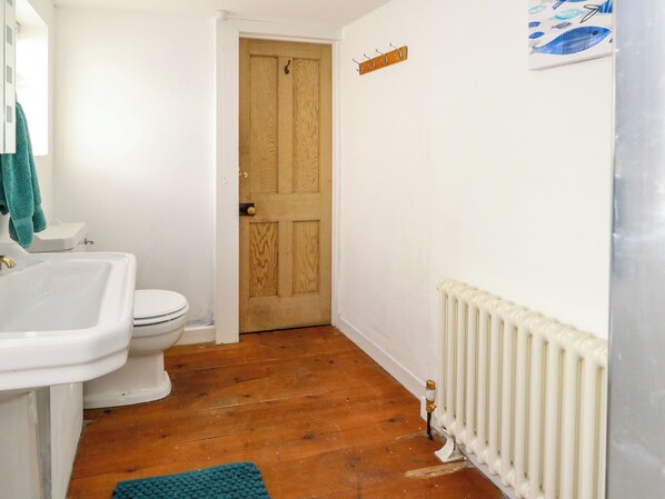 Une salle de bain avec un lavabo blanc, des toilettes et une porte en bois.