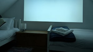 Quarto com duas camas, uma janela grande e mesa de cabeceira com abajur.