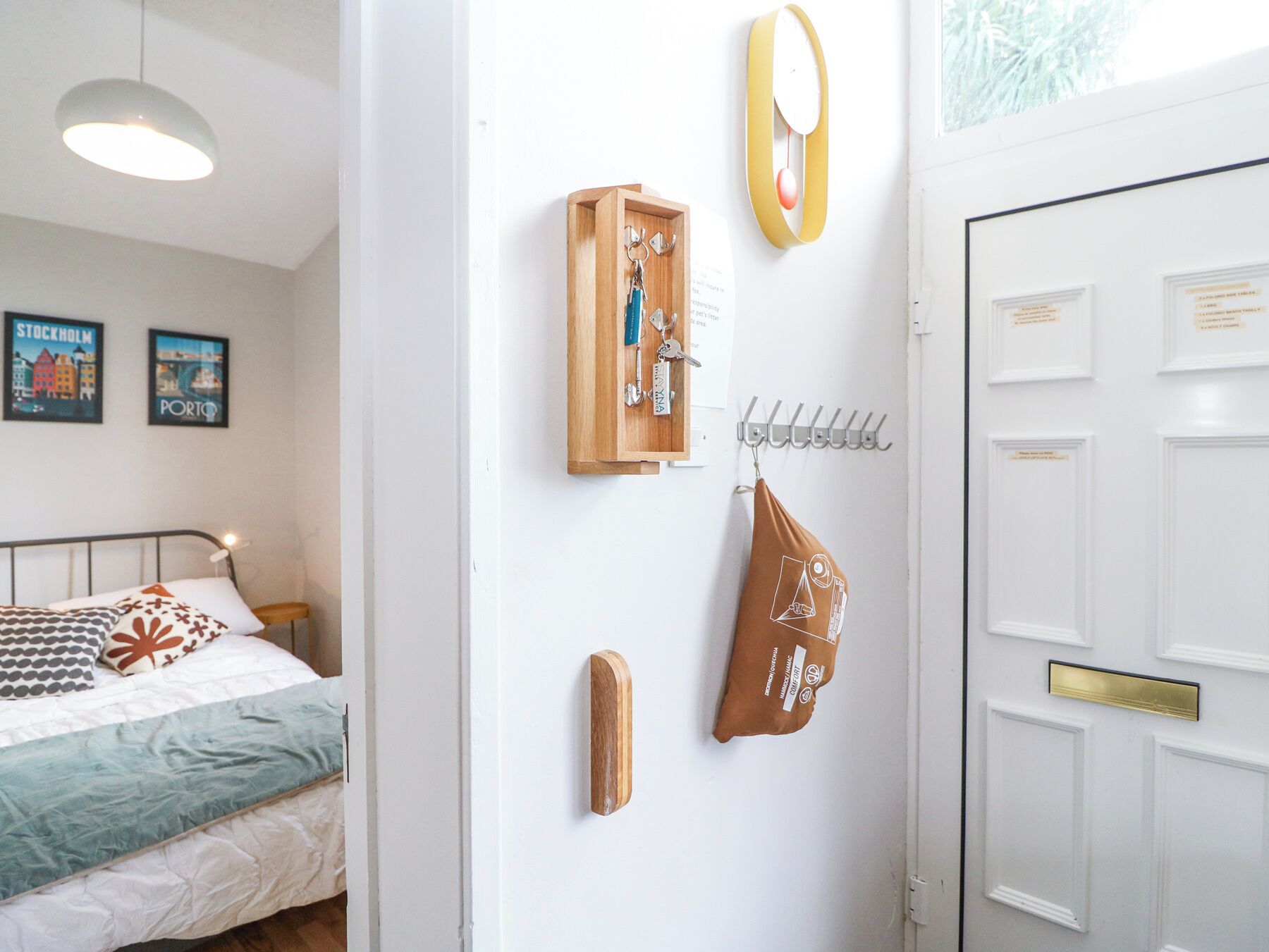 Un dormitorio con una cama, un armario de madera con llaves, un abrigo colgado de un gancho y una puerta con buzón.