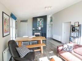 A modern living room with a fireplace, a dining area, and a bookshelf.