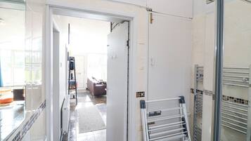 A hallway with a white door leading to a living area, a white towel rack, and a tiled floor.
