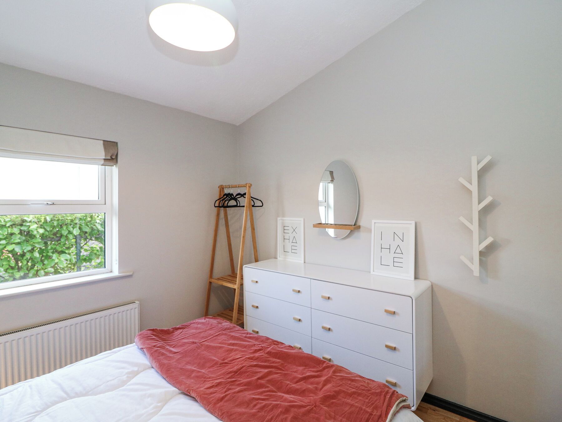 Ein Schlafzimmer mit einem Bett, einem Schminktisch, einem Spiegel und einem Fenster.