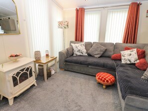 Ein Wohnzimmer mit Sofa, Hocker und einem kleinen Tisch mit Dekoration.