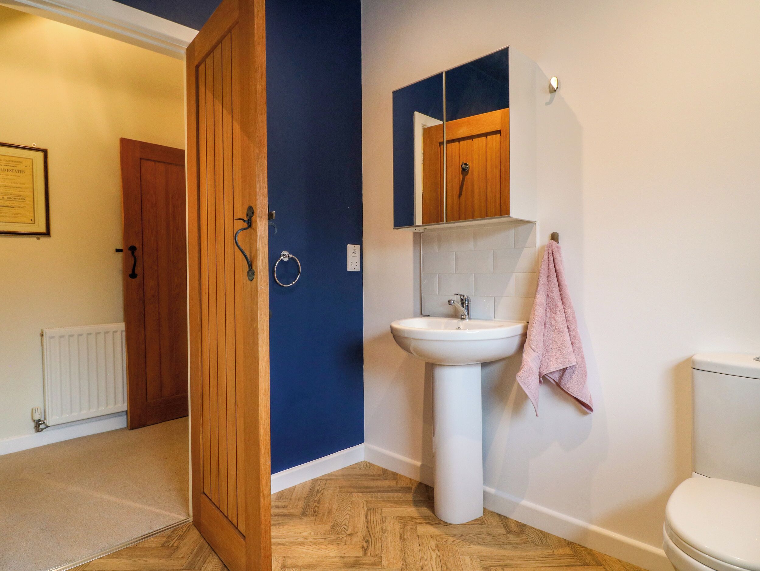 A bathroom with a wooden door, a white sink, and a toilet.