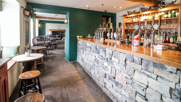 A bar area with a stone counter, multiple taps, and a variety of bottles and glasses. - Apartment at The Old Dog, Thorpe (Ashbourne)