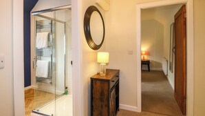 A hallway with a glass shower, a wooden cabinet with a lamp, and a mirror on the wall. - Apartment at The Old Dog, Thorpe (Ashbourne)