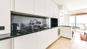 A modern kitchen with white cabinets, a black countertop, and a large window providing a view of the outdoors.