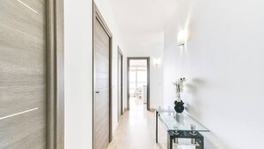 A hallway with a glass table, a vase with flowers, and a door.