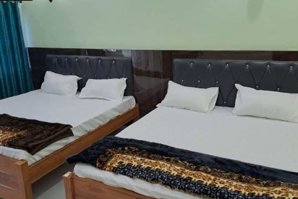 Une chambre d’hôtel avec deux lits, chacun doté d’une tête de lit sombre et de draps blancs.