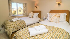 Habitación de hotel con dos camas, una ventana con cortinas, una lámpara de noche y vistas a edificios.