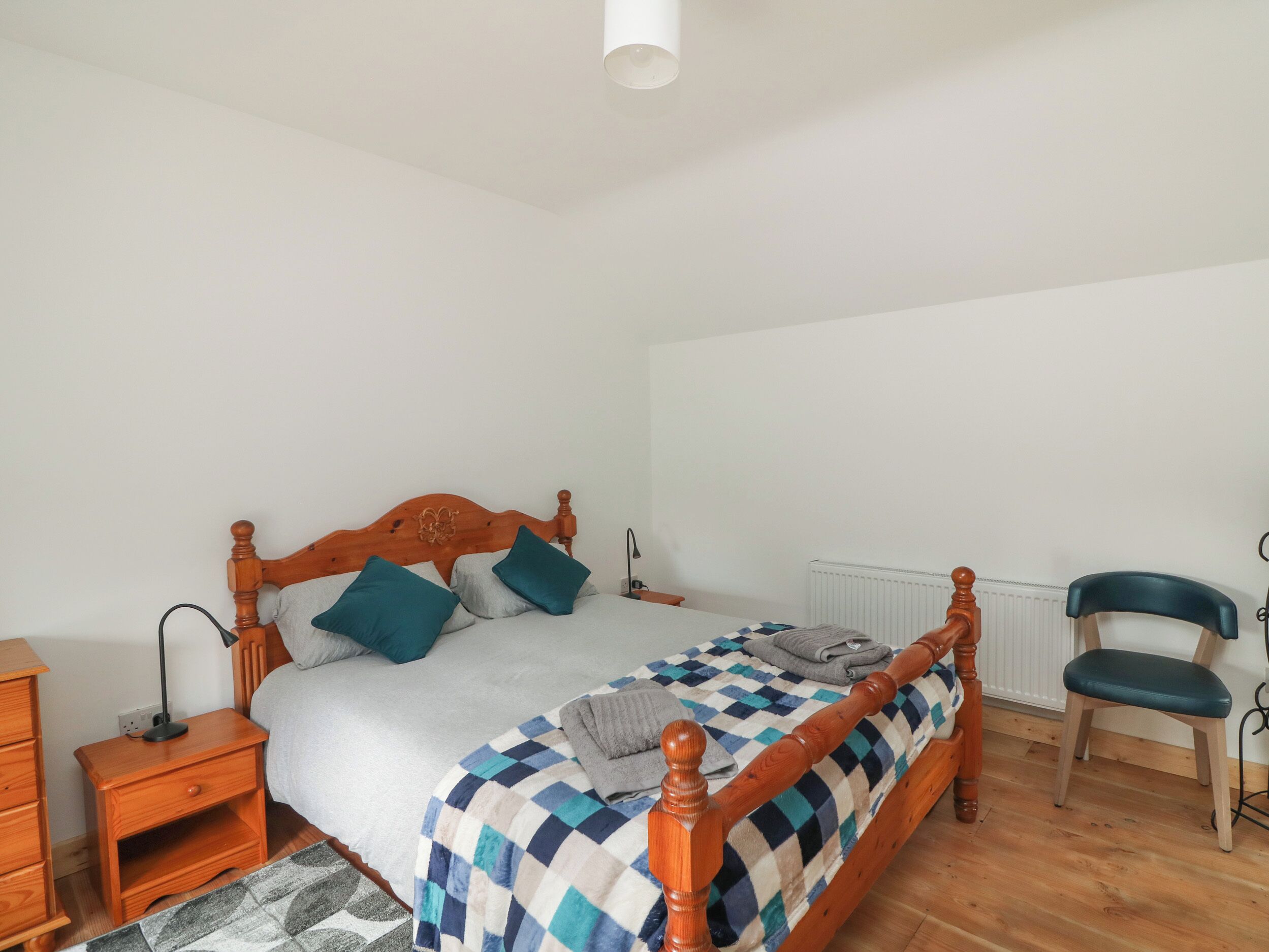 Una camera da letto con un letto in legno, un comodino, una sedia e un termosifone.