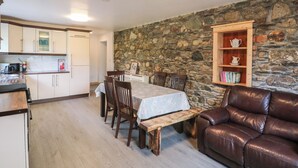 Une cuisine chaleureuse avec un mur en pierre, des meubles en bois et une table à manger.