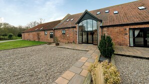 A brick building with a tiled roof, large glass doors, and a gravel driveway. - Coot (Beccles)