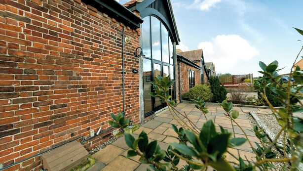 A brick building with a large glass window and a stone pathway. - Coot (Beccles)