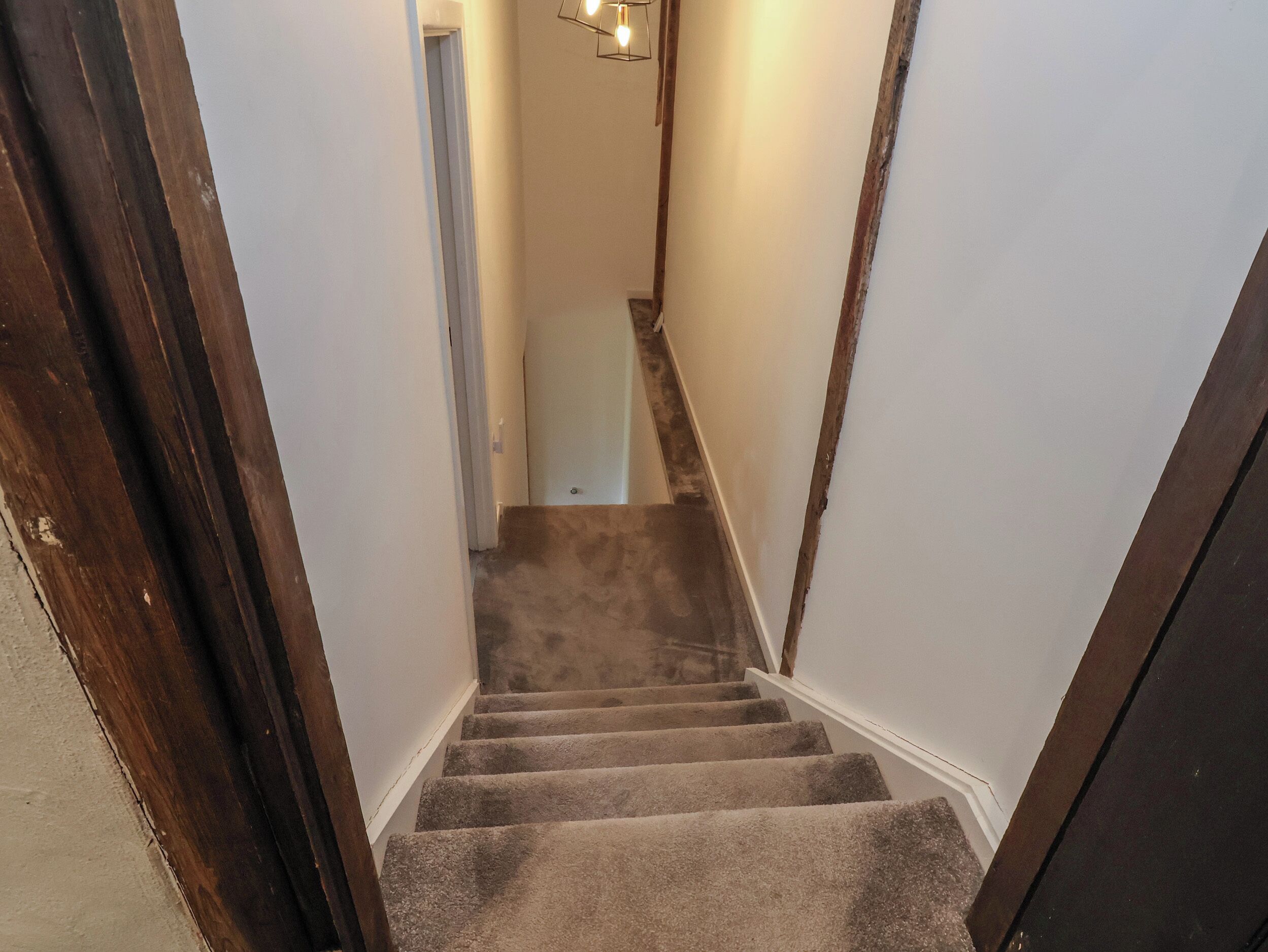A carpeted staircase with wooden handrails, leading to a door at the top.