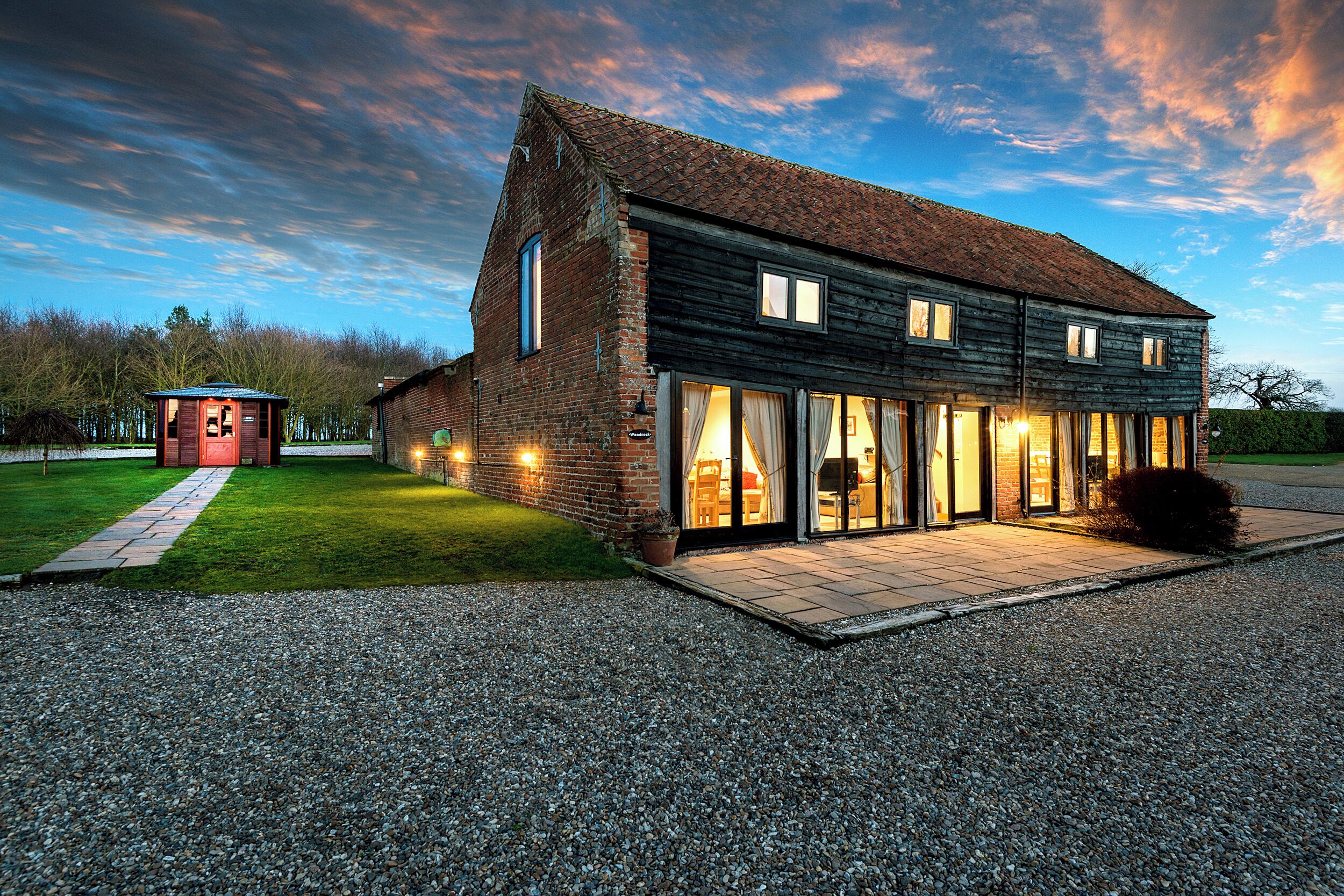 A large, modern house with a spacious patio and a small adjacent structure.