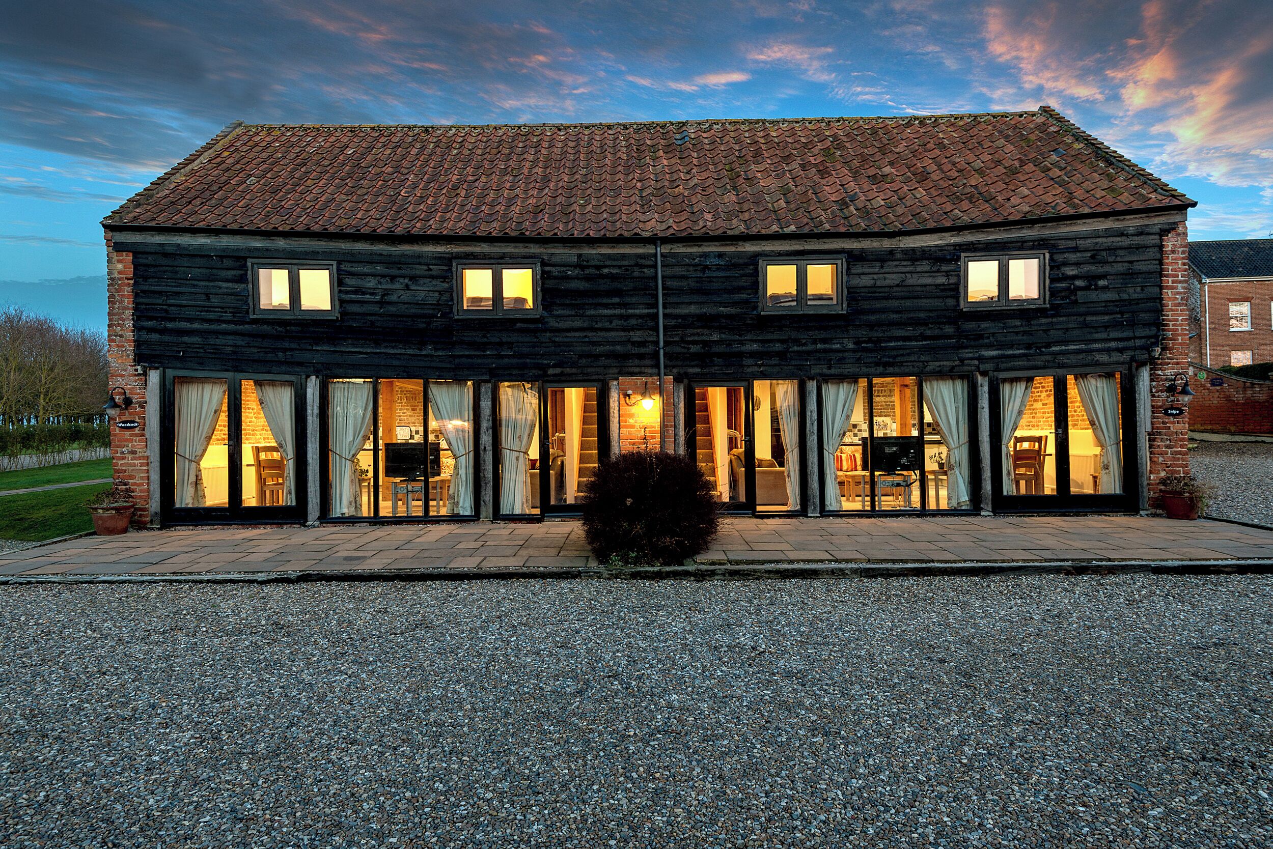A two-story wooden building with large windows and a gravel driveway.
