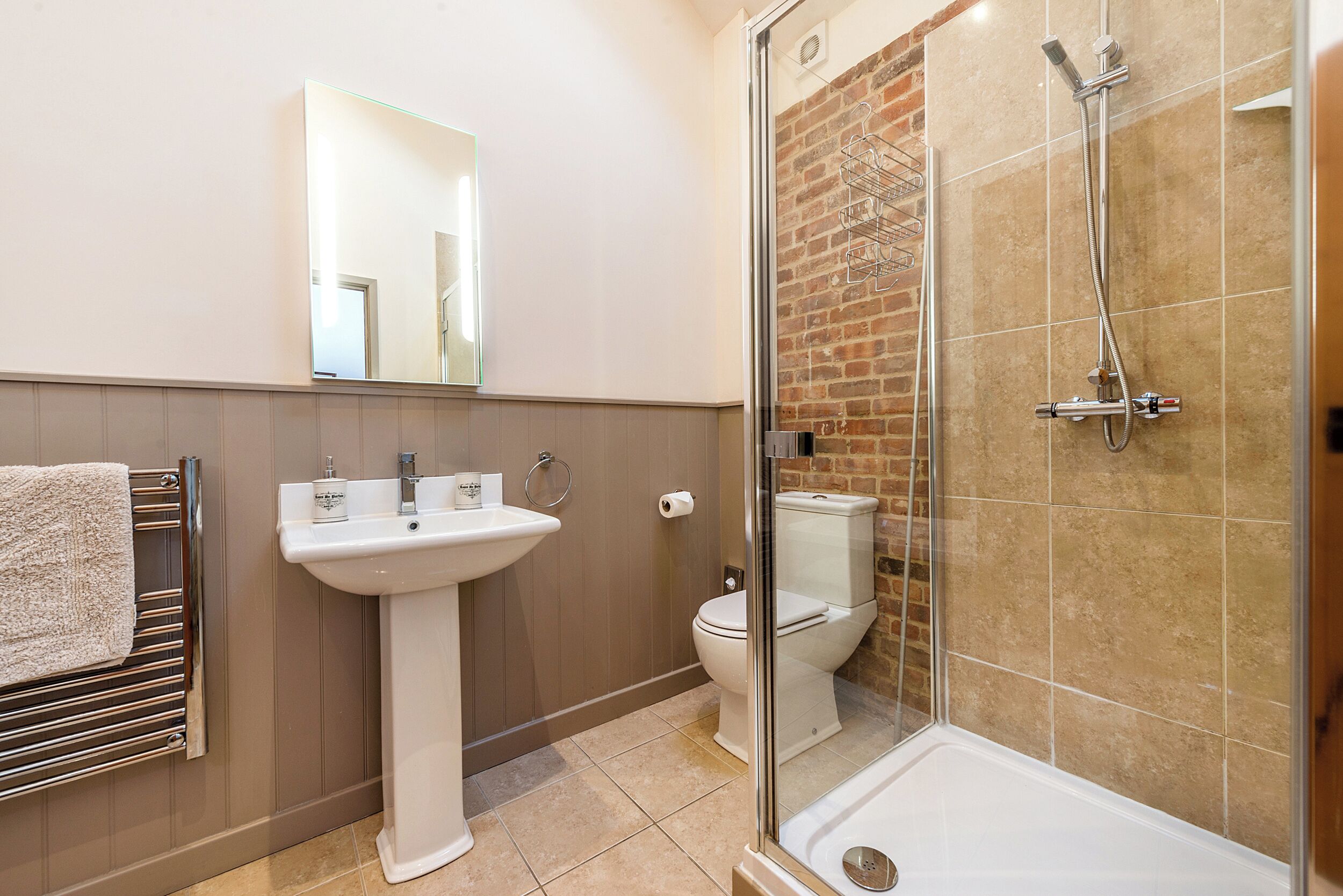 Een moderne badkamer met een douchecabine, een wastafel op een voetstuk en een toilet.