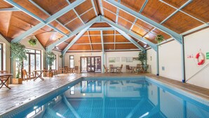 An indoor swimming pool with wooden beams and a high ceiling. - Caravan 7 (Plymouth)