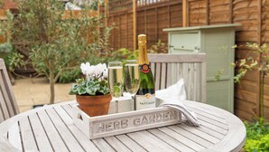 Una mesa de madera con un cartel que dice "HERB GARDEN", una botella de champán y dos copas encima.