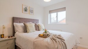Un dormitorio ordenado con cama, mesita de noche y ventana.