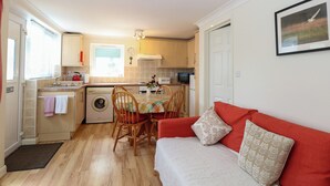 A compact living space with a kitchenette, a dining area, and a sofa. - Paws-a-while (Norwich)