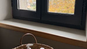 A room with a window overlooking a tree with autumn foliage. A wicker basket with bottles is placed on the windowsill. - Charming house, Close to Geneva, Annecy, ski slopes, at the foot of the Salève mountains (etrembiers)