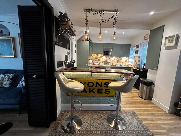 Une cuisine moderne dotée d’un coin bar, d’un four à micro-ondes et d’un évier.