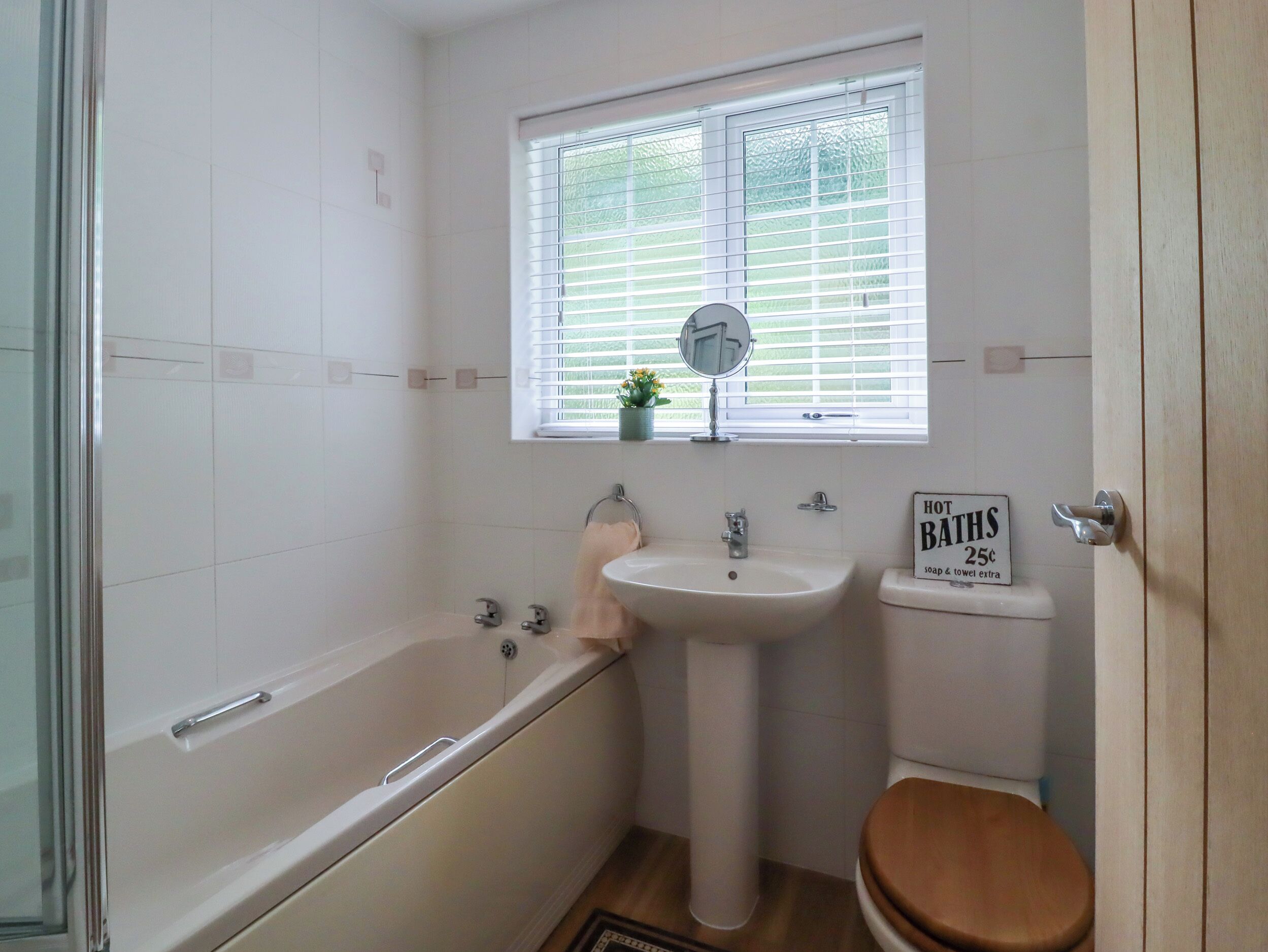 A bathroom with a bathtub, sink, toilet, and a window with blinds.