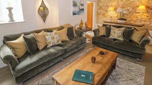 A living room with two sofas, a coffee table, and a stone wall. - Bay House Cottage (Broadway)
