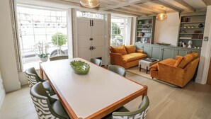 A dining area with a table, chairs, and a green bowl centerpiece. - Bay House Cottage (Broadway)