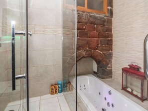 A bathroom with a glass shower enclosure, a stone fireplace, and a bathtub with a red lantern. - Monastery Hall (Chester)